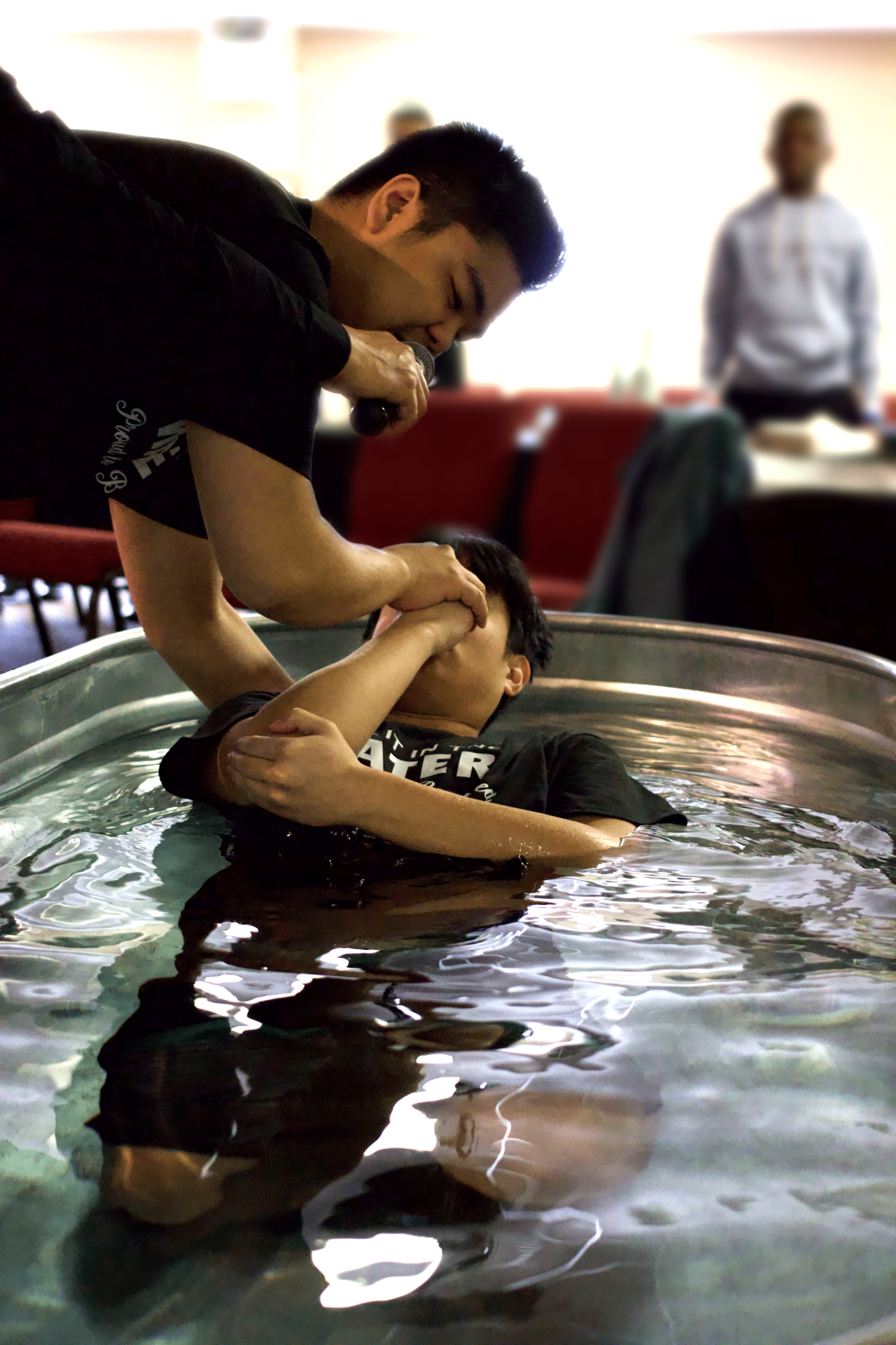 Person immersed in water during baptism ceremony.